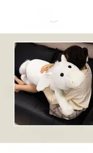 Detailed view of large white plush horse pillow with soft wings on a black leather sofa