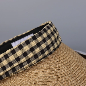 Detailed macro view of woven straw texture and yellow plaid fabric ribbon on sun hat