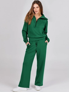 Detail of green two-piece tracksuit featuring half-zip sweatshirt and wide-leg sweatpants