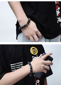 Detailed view of volcanic lava stone bracelet with engraved silver beads on male wrist
