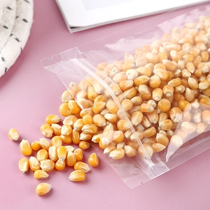 Clear plastic resealable food storage bag filled with yellow corn on pink background