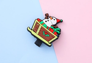Detail of Christmas snowman and sleigh PVC charms on pink and blue background