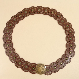 Flat lay of a brown western punk belt with round riveted discs and embossed metal buckle