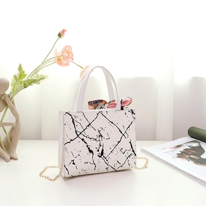 Detailed view of a white marble texture handbag with colorful silk scarf and gold chain strap