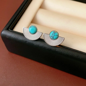 Close-up of vintage fan-shaped turquoise stud earrings in silver on black leather