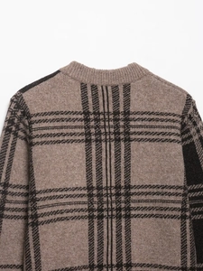Close-up of crew neck ribbed collar and brown plaid knit pattern on the sweater