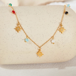 Detail of gold star pendant necklace with colorful beads on a ceramic stand