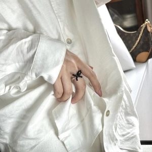 Detail of beaded black cross ring worn by a model in a clean lifestyle setting