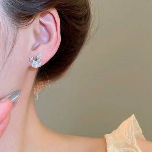 Close-up of minimalist silver rabbit stud earrings with zircon inlay worn by model