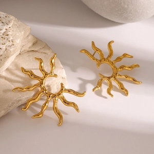 Detailed view of sunburst gold stud earrings on stone with elegant natural lighting