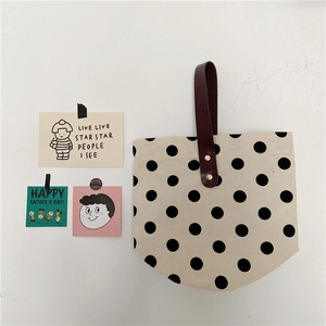 Close-up of retro polka dot canvas bag with leather handle and gold rivet details