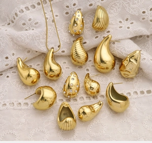 Detailed close-up of 18K gold teardrop earrings and pearl necklace on lace fabric