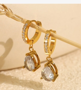 Gros plan de boucles d'oreilles goutte dorées avec zircons sur branche naturelle