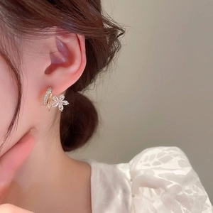 Détail de boucles d'oreilles fleurs dorées avec pétales sertis de zircons brillants