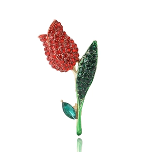 Elegant gold tulip brooch with sparkling red and green crystals on white background