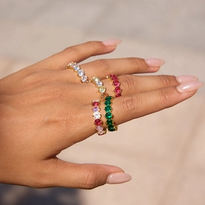 Close-up of colorful round zircon stackable rings on a hand with a luxury gold finish