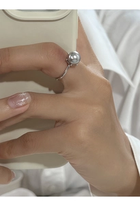 Dettaglio di un anello regolabile in argento S925 con una perla grigia sulla mano di una donna