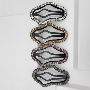Detailed view of four rhinestone snap hair clips in silver, gold, pink and grey