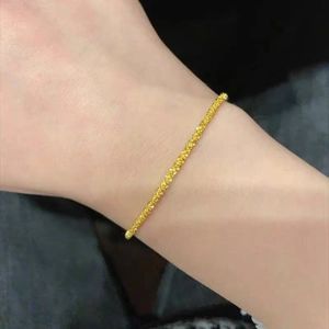 Detailed view of a slender gold textured bracelet sparkling on a woman's wrist