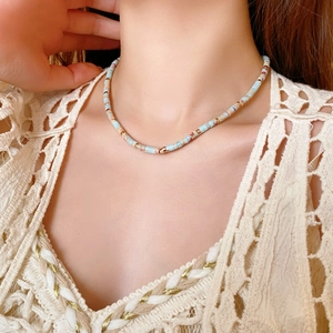Detailed view of a round blue Shoushan stone necklace on a model with lace top