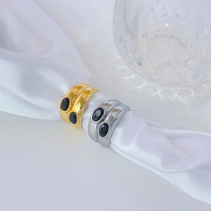 Detail of wide band steel rings with dual black stones on white silk background
