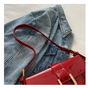 Detail of adjustable red patent leather strap with gold buckle on a shoulder bag
