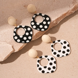Vintage black and white polka dot geometric earrings set on natural stone background