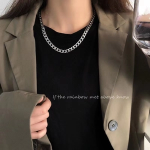 Close-up of silver Cuban link chain necklace on model wearing a suit and black t-shirt