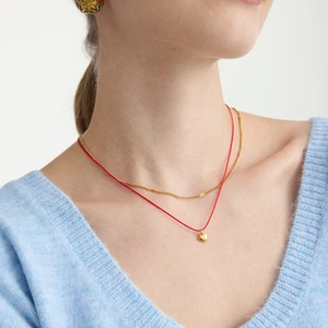 Collier double couche en acier doré 18K avec pendentif cœur et cordon rouge sur modèle