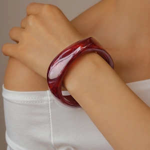 Macro shot of wide resin bangle featuring red marble texture on woman's wrist