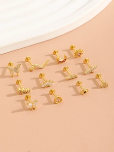 Macro shot of assorted gold piercing studs with butterfly and moon designs on sand background