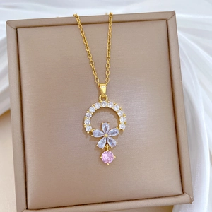 Detail of floral pendant with blue and pink stones in a beige jewelry box on white silk