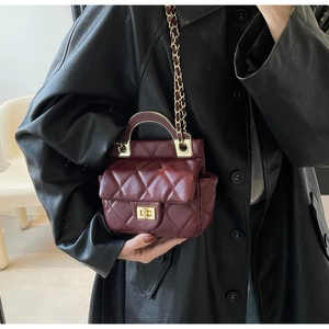 Detail of burgundy quilted leather handbag with gold twist lock and chain strap