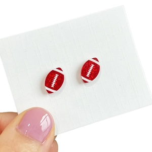 Glittery red football helmet earrings on card holder shown from a front-facing angle