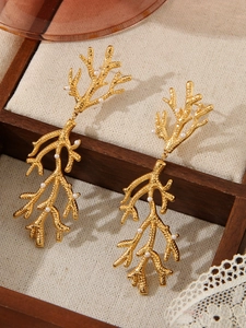 Détail de boucles d'oreilles branche dorées avec perles dans un écrin vintage