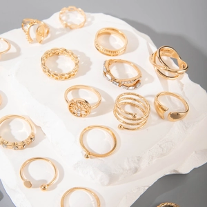 Detail shot of vintage gold rings with crystal and chain designs on a stone surface