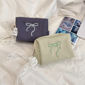 Detail of canvas makeup bag with bow embroidery and metal zipper closure