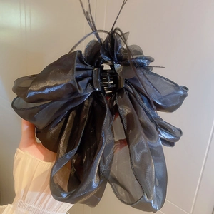 Détail de la pince à cheveux noeud en organza noir avec accents de plumes