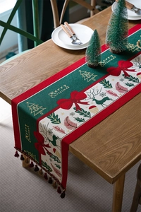 Christmas table runner with deer and tassels on a wooden table for festive decoration