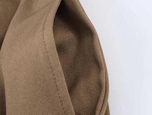 Detailed macro view of dark khaki midi skirt fabric with twill texture and double stitching