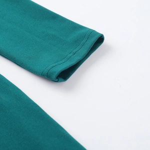 Détail des poignets en tricot vert paon avec couture précise à double aiguille sur les manches