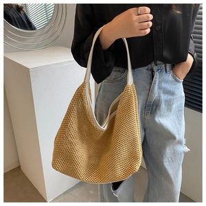 Close-up of khaki woven tote bag with white trim and mesh hollow design on model