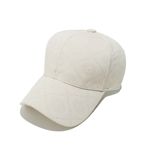 Détail de casquette crème avec texture tournesol matelassée en 3D et visière courbée
