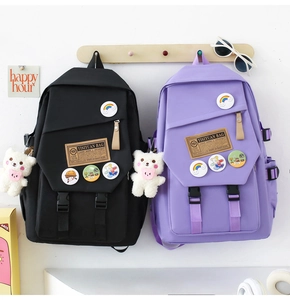 Detail of nylon school backpacks in black and purple with cute bear charms and badges