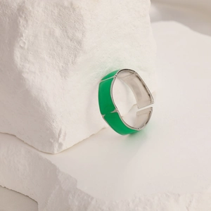Detail view of silver ring with green enamel square sections on a white stone base