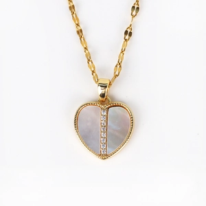 Macro detail of a heart-shaped shell pendant with sparkling zircon in gold finish
