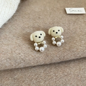 Detailed macro shot of white flocked puppy earrings with gold bow and pearl hoop detail