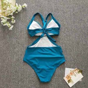 Peacock blue monokini detail with crisscross back straps and cutout design on flat lay