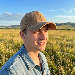 Khaki brown herringbone wool baseball cap with crown badge shown on a male model outdoors