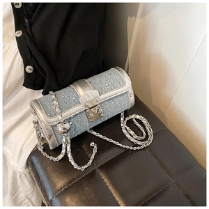 Detail of blue denim barrel bag featuring sparkling rhinestones and a silver M-buckle